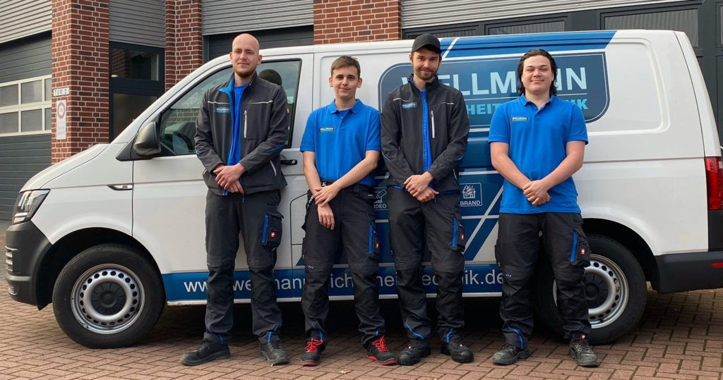Vier neue Auszubildende stehen vor dem Firmenwagen am Firmensitz Wellmann Sicherheitstechnik Hamminkeln Kreis Wesel