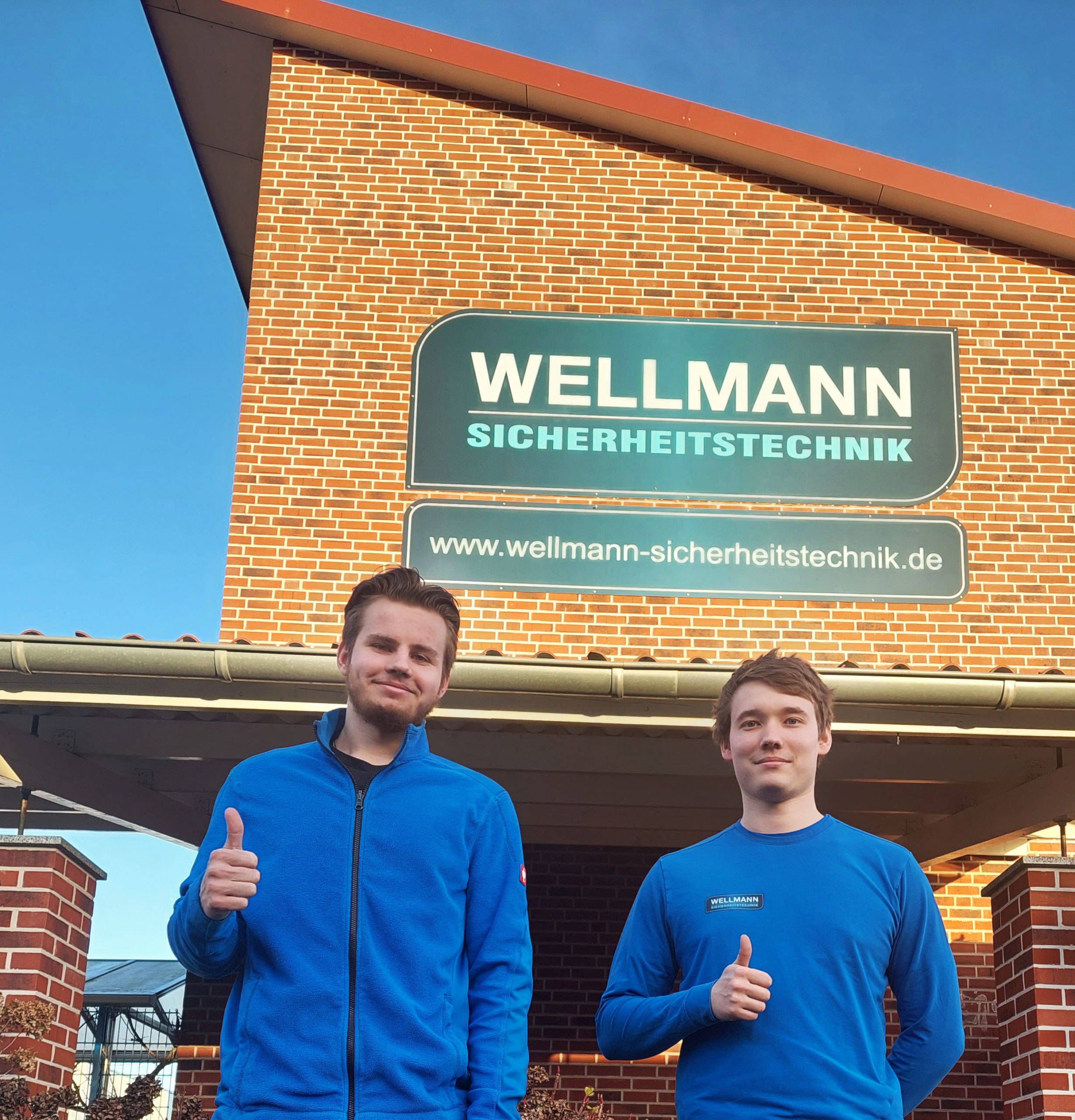 Auszubildene haben Gesellenpruefung bei Wellmann Sicherheitstechnik bestanden und stehen vor dem Firmensitz in Hamminkeln